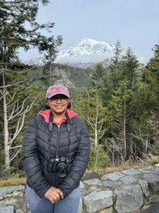 solo female traveler sitting on a stone wall with a back drop of Mt. Rainier in Mt. Rainier National Park